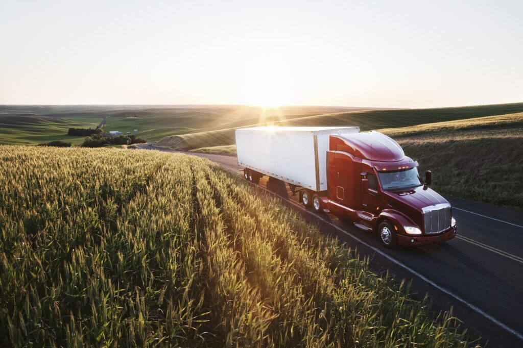 commercial truck driving though wheat fields of eastern Washington, USA at sunset.